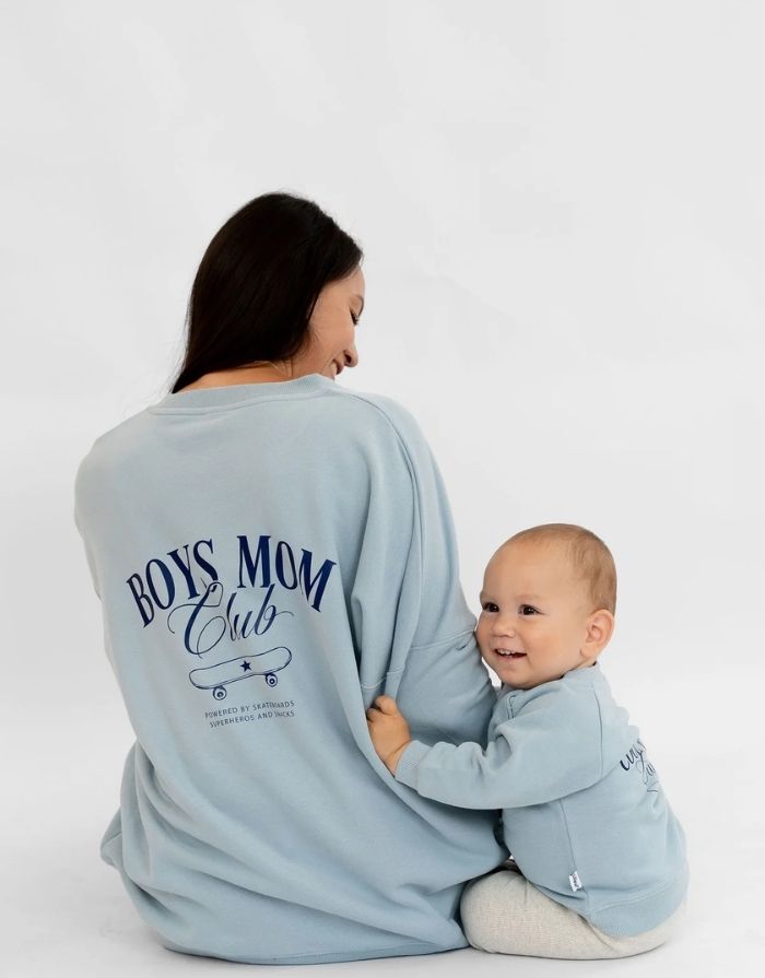  Liliput Boys Mom Club Oversize Sweatshirt für Damen mit dezentem Brustprint und großem Skateboard-Schriftzug auf dem Rücken, getragen.