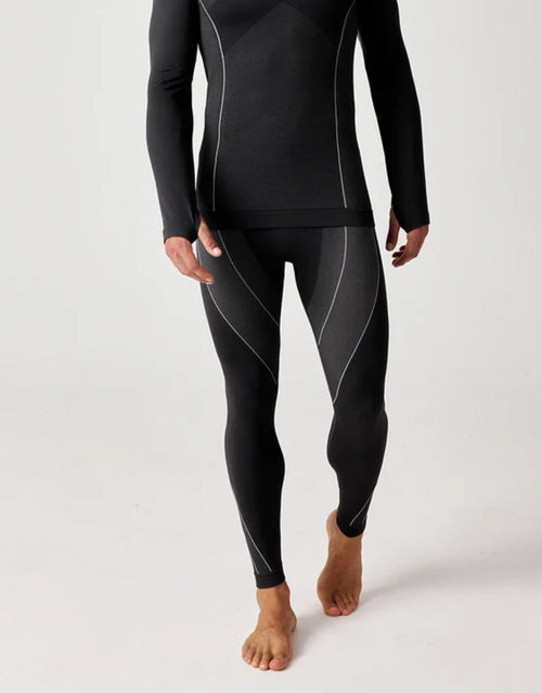 Schwarze Thermounterhose für Herren von SNOCKS aus elastischem, recyceltem Funktionsmaterial mit körpernaher Passform für angenehme Wärme an kalten Tagen, am Model.