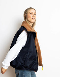 Reversible Bomber Weste von Vivi Mari in Navy und Karamell, tragbar mit glattem Nylon oder weichem Fleece außen, oversized geschnitten mit Reißverschluss und Taschen, ideal für Layering und urbane Looks.