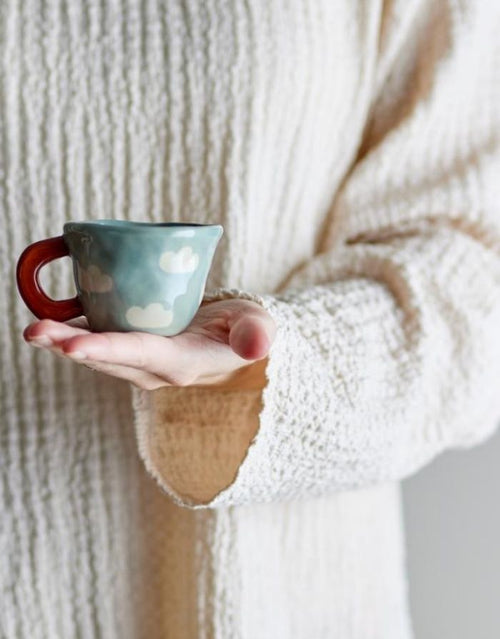 Blaue Tasse Nini von Bloomingville MINI aus Steingut mit handgemaltem Wolkenmotiv und 110 ml Fassungsvermögen.