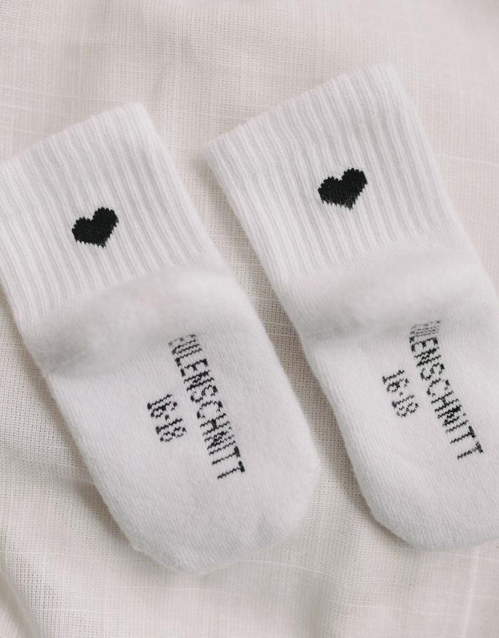 Weiße Babysocken Herz Schwarz von Eulenschnitt mit eingesticktem schwarzem Herz und weicher Baumwollqualität für Babys.