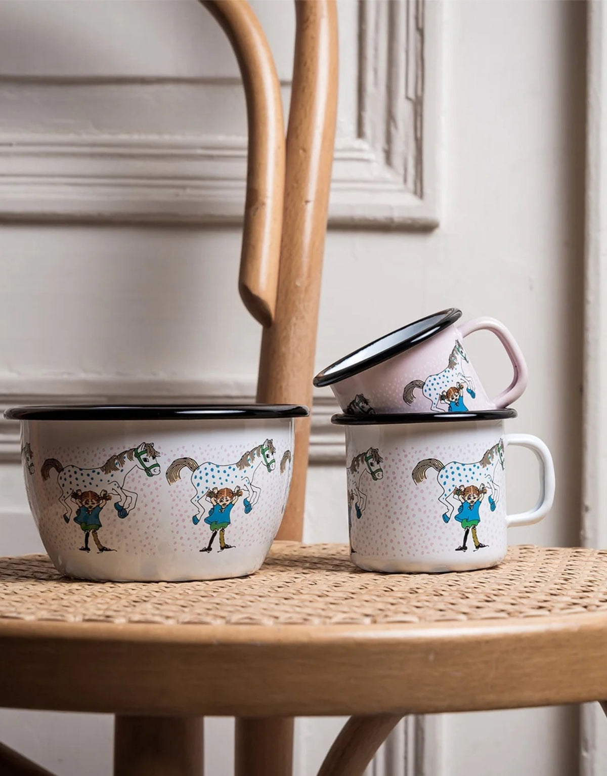 Pippi Langstrumpf Emaille-Becher von Muurla mit Pippi und ihrem Pferd Kleiner Onkel, dekorativer Trinkbecher aus emailliertem Stahl mit Henkel und 250 ml Fassungsvermögen auf einem Stuhl