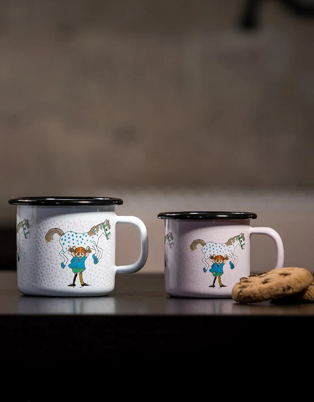 Pippi Langstrumpf Emaille-Becher von Muurla mit Pippi und ihrem Pferd Kleiner Onkel, dekorativer Trinkbecher aus emailliertem Stahl mit Henkel und 250 ml Fassungsvermögen neben Keksen