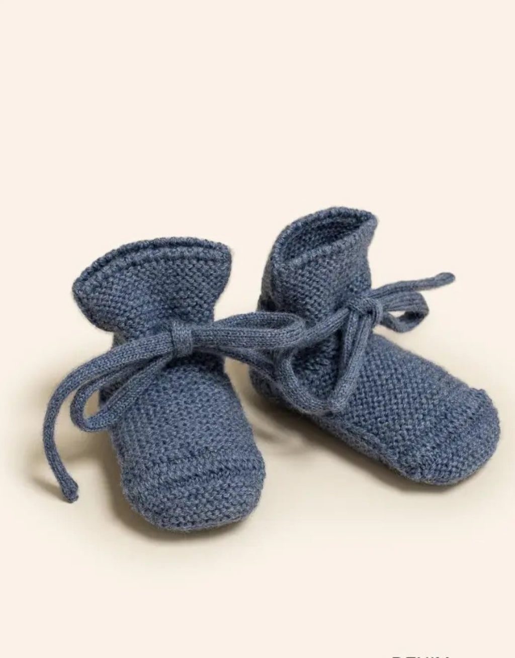 Booties von Hvid aus Merinowolle in der Farbe Denim für Babys im Alter von 09 Monate auf gelbem Hintergrund