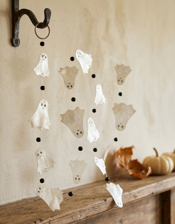 Weiße Halloween Girlande Ghostie von BOLTZE mit handgefertigten Gespenstern aus Capiz, 180 cm lang, vor einer Wand.