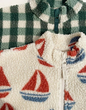 Laden Sie das Bild in den Galerie-Viewer, Die Teddyjacke Jody Ahoy von Konges Sløjd ist ein kuscheliger Begleiter für kalte Tage und aktive Abenteuer im Freien. Das weiche Teddy-Material aus recyceltem Polyester hält angenehm warm, während das innenliegende Fleece für zusätzlichen Komfort sorgt. Mit ihrem hohen Kragen schützt die Jacke zuverlässig vor Wind, und die elastischen Ärmelbündchen sorgen für einen guten Sitz. Der durchgehende Frontreißverschluss macht das An- und Ausziehen besonders einfach – ideal für den Alltag mit Kindern. Das Ahoy-Des
