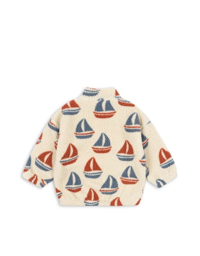 Die Teddyjacke Jody Ahoy von Konges Sløjd ist ein kuscheliger Begleiter für kalte Tage und aktive Abenteuer im Freien. Das weiche Teddy-Material aus recyceltem Polyester hält angenehm warm, während das innenliegende Fleece für zusätzlichen Komfort sorgt. Mit ihrem hohen Kragen schützt die Jacke zuverlässig vor Wind, und die elastischen Ärmelbündchen sorgen für einen guten Sitz. Der durchgehende Frontreißverschluss macht das An- und Ausziehen besonders einfach – ideal für den Alltag mit Kindern. Das Ahoy-Des