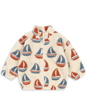 Laden Sie das Bild in den Galerie-Viewer, Die Teddyjacke Jody Ahoy von Konges Sløjd ist ein kuscheliger Begleiter für kalte Tage und aktive Abenteuer im Freien. Das weiche Teddy-Material aus recyceltem Polyester hält angenehm warm, während das innenliegende Fleece für zusätzlichen Komfort sorgt. Mit ihrem hohen Kragen schützt die Jacke zuverlässig vor Wind, und die elastischen Ärmelbündchen sorgen für einen guten Sitz. Der durchgehende Frontreißverschluss macht das An- und Ausziehen besonders einfach – ideal für den Alltag mit Kindern. Das Ahoy-Des
