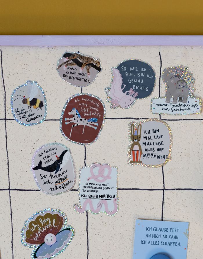 Glitzersticker von Liesels Wicht mit liebevollem Motiv und motivierender Botschaft für Kinder auf glänzendem Glitzervinyl vor einer Wand.