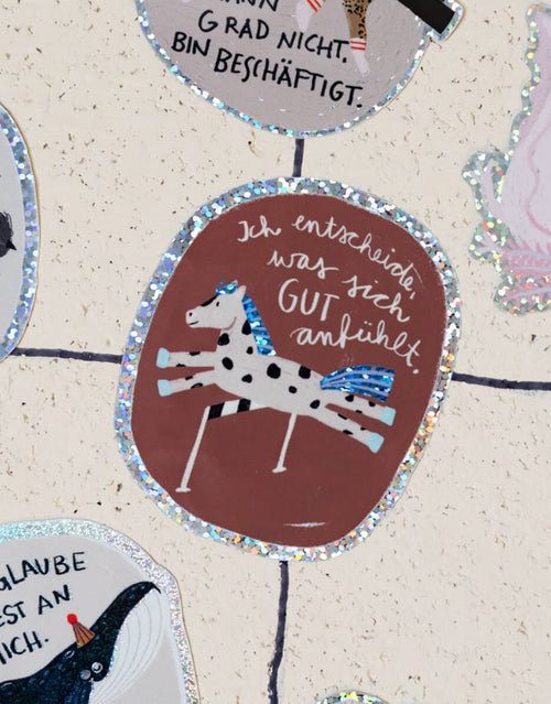 Glitzersticker von Liesels Wicht mit liebevollem Motiv und motivierender Botschaft für Kinder auf glänzendem Glitzervinyl auf einer Wand.