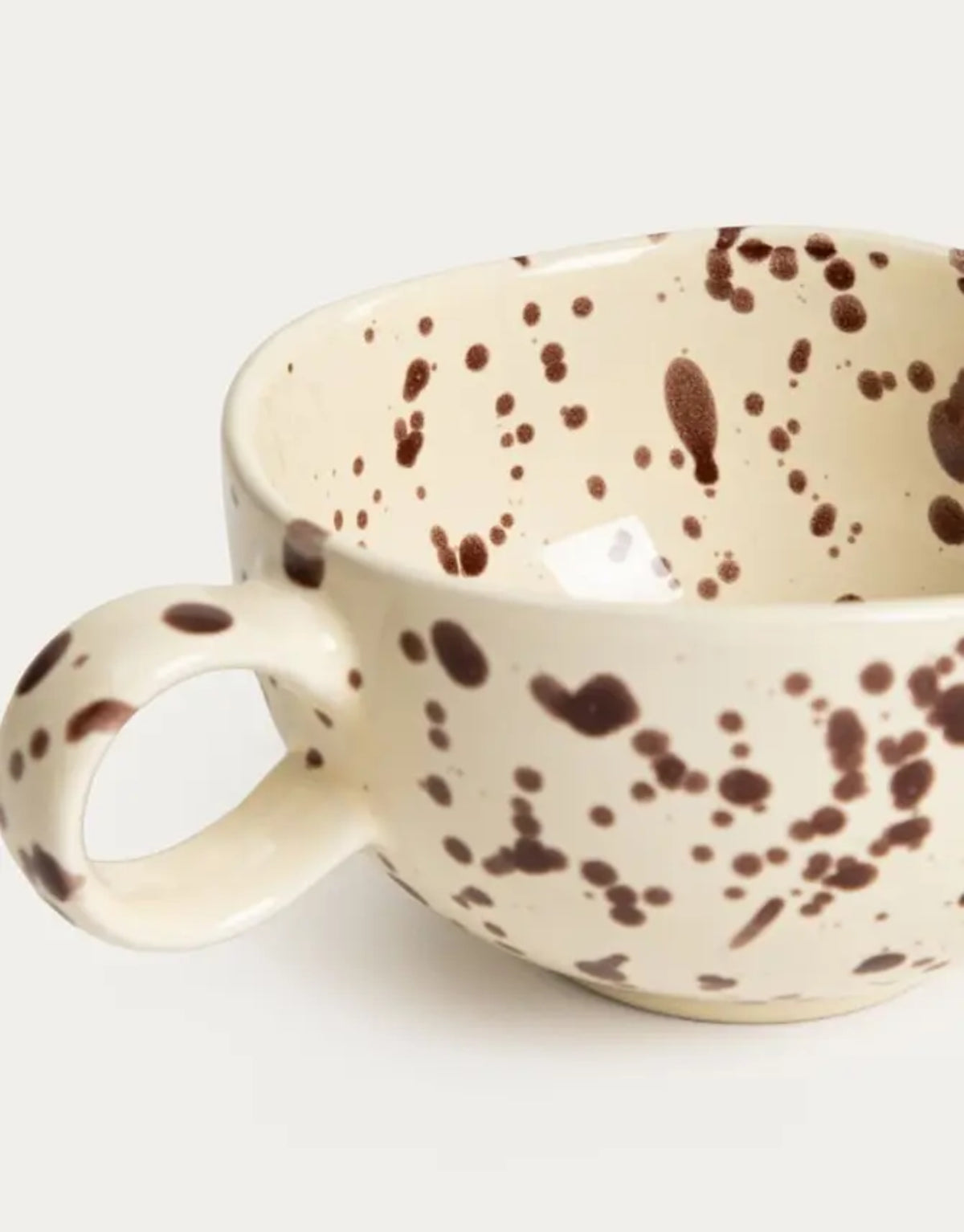 Becher Kenki von HOMLA in Ecru, 300 ml großer Keramikbecher aus Steingut mit unregelmäßigen schwarzen Sprenkeln, abgerundeter Form und individueller reaktiver Glasur.