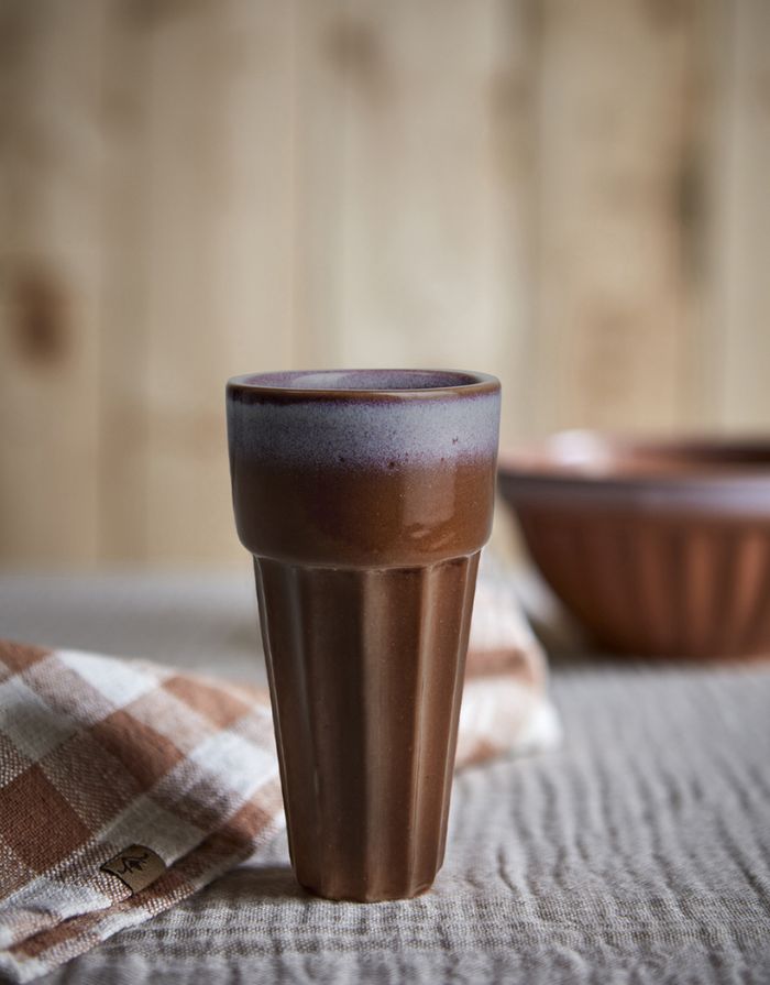 Becher Costa L von Affari of Sweden aus Steingut in Terracotta mit individueller Farbgebung und Musterung, Ø 8 × H 14 cm, auf einem Tisch.