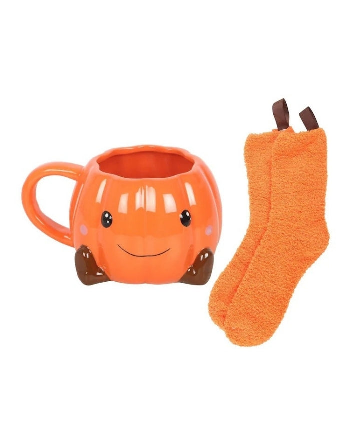 Halloween Geschenkset von Something Different mit orangefarbener Kürbistasse mit Gesicht und passenden flauschigen Socken mit den Socken daneben 