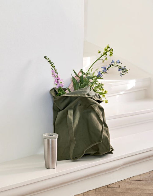 Rosendahl Grand Cru Outdoor Thermobecher in Sand aus Edelstahl mit 360-Grad-Trinkdeckel und 400 ml Fassungsvermögen auf einer Treppenstufe.