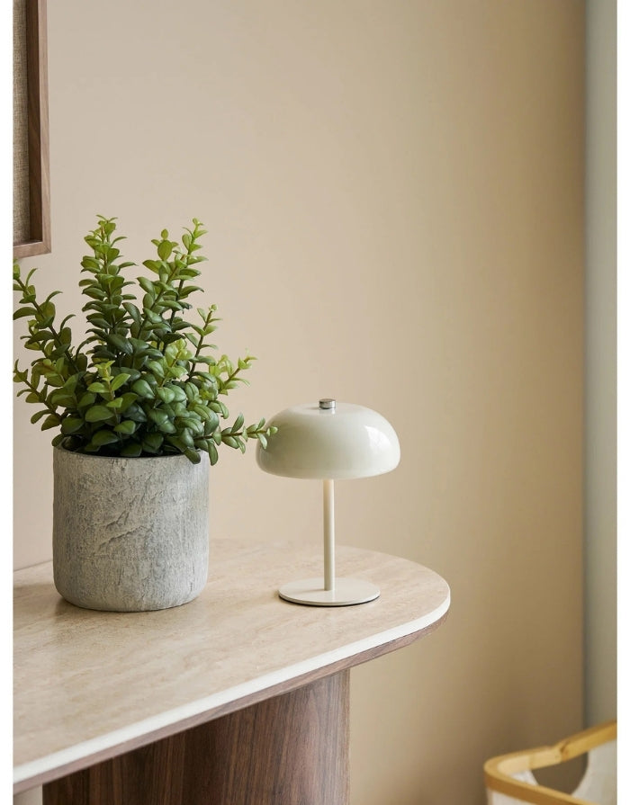 Portable Tischlampe Margate von House Nordic in Beige aus Metall mit fest verbauter LED und wiederaufladbarem Akku neben einer Pflanze