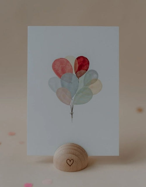 Postkarte von Eulenschnitt in weiß mit bunten Luftballons in einem Kartenständer