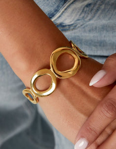 Goldfarbener Armreif im Retro-Stil mit offenen, kreisförmigen Elementen.
Aus 14K-vergoldetem, wasserfestem Edelstahl.