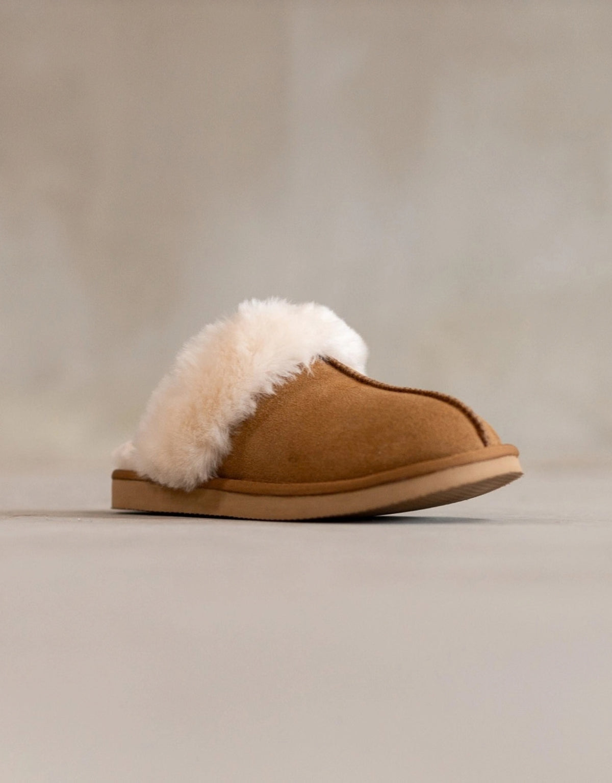 Lumi Slipper aus echtem Wildleder mit weichem Schafwollfutter, sichtbarem Wollkragen und robuster Gummisohle als Freisteller von schräg