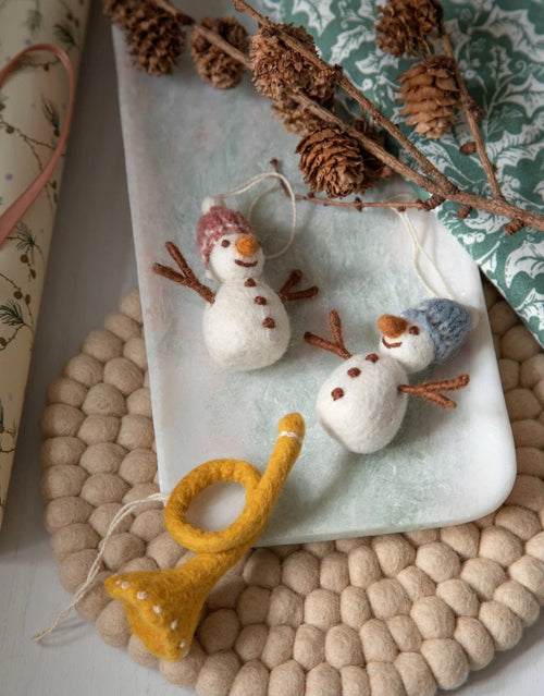 Anhänger Schneemann Bunt von Gry und Sif, handgefertigter Weihnachtsanhänger aus neuseeländischer Wolle in verschiedenen Farben und mit individuellen Details, 8 cm hoch, Farbauswahl zufällig auf einem Teller