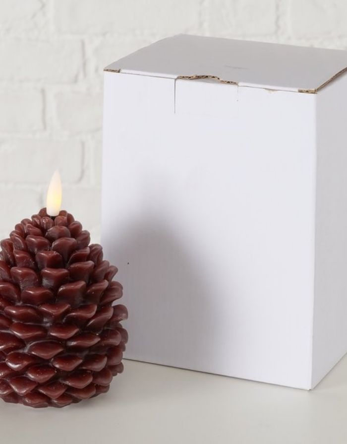 Braune LED-Kerze Pinio von BOLTZE in Zapfenform aus Wachs mit warmweißem Licht, Timer und Fernbedienung, mit Verpackung.