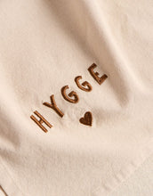 Laden Sie das Bild in den Galerie-Viewer, Leinenfarbenes Geschirrtuch mit „Hygge“-Schriftzug von Ib Laursen, Größe 50x70 cm.
