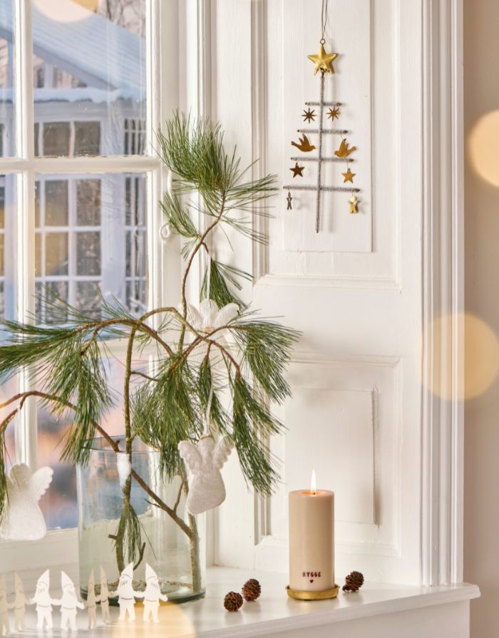 Rustikale weiße Stumpenkerze mit braunem „Hygge“-Schriftzug.