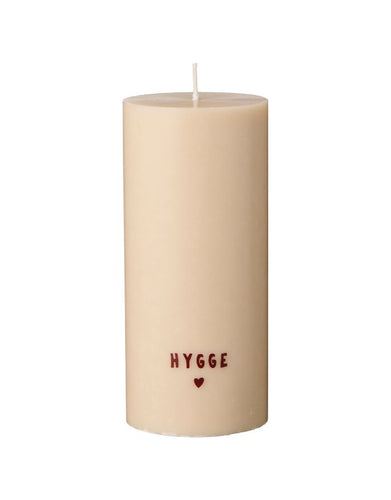 Rustikale weiße Stumpenkerze mit braunem „Hygge“-Schriftzug.