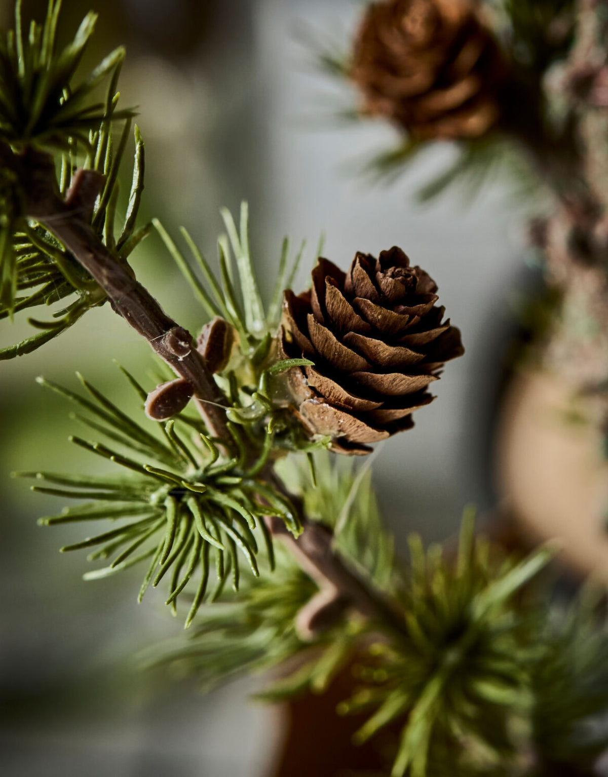 Grüner künstlicher Weihnachtsbaum Stay von House Doctor in natürlicher Zedernoptik mit feinen Zweigen und kleinen Zapfen, 40 cm hoch im Detail mit Hintergrund