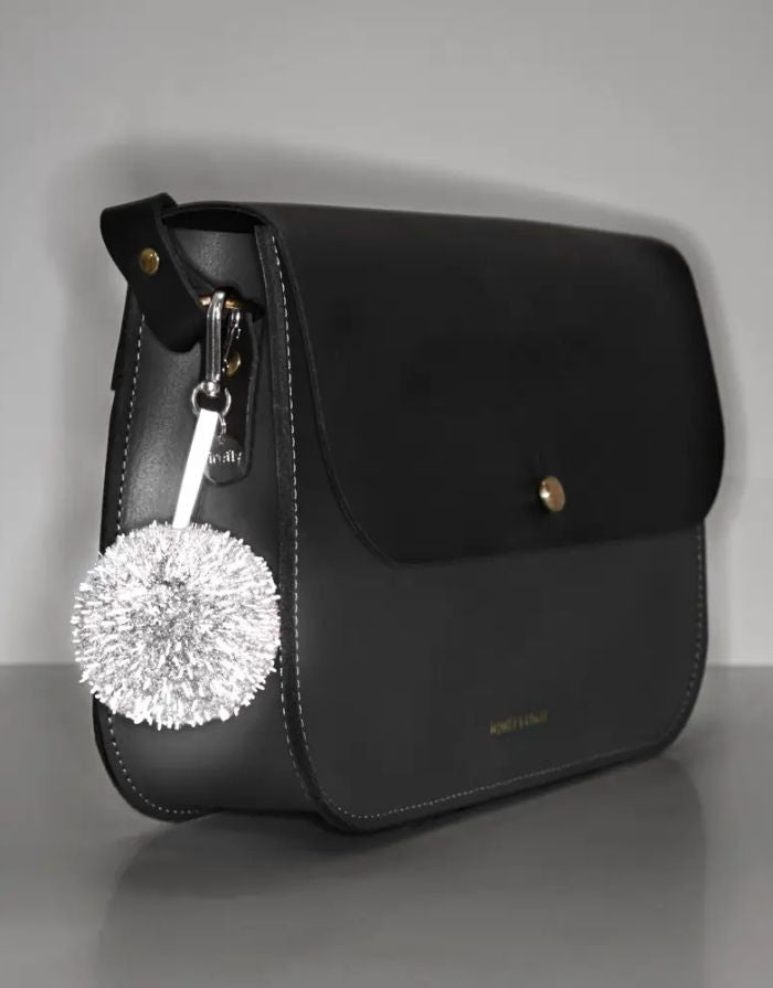 Reflektierender Pom Pom Anhänger in Rosa von Firefly Reflectors aus flauschigem Garn mit reflektierendem Faden und Band – stilvolles Accessoire für Taschen und Rucksäcke.
