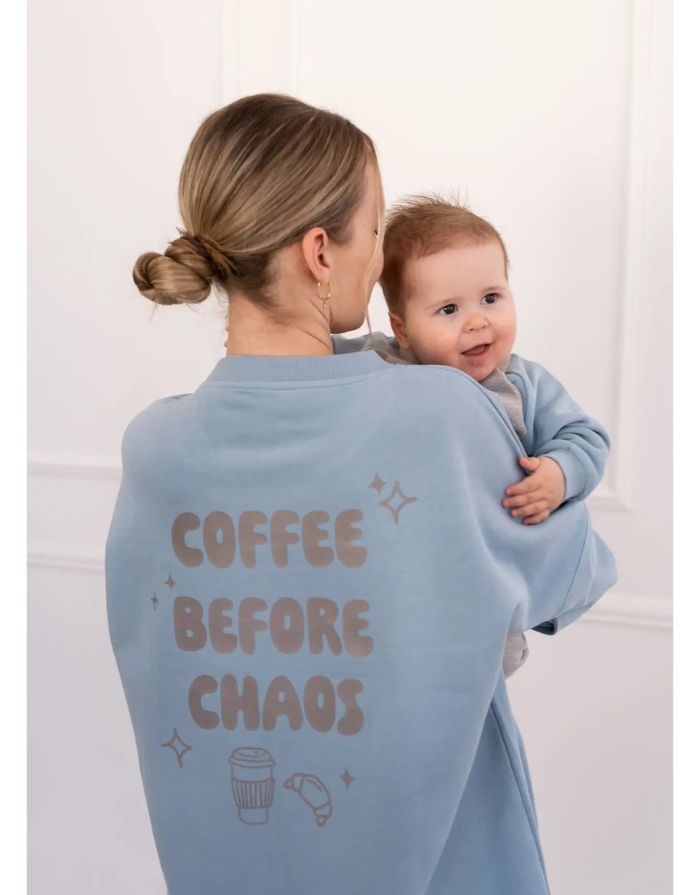Fliederfarbenes Oversized Sweatshirt von Liliput mit „6am“-Print auf der Brust und großem Rückenschriftzug „Coffee before the Chaos evolves“ – gemütlich und stylisch für den Eltern-Alltag.